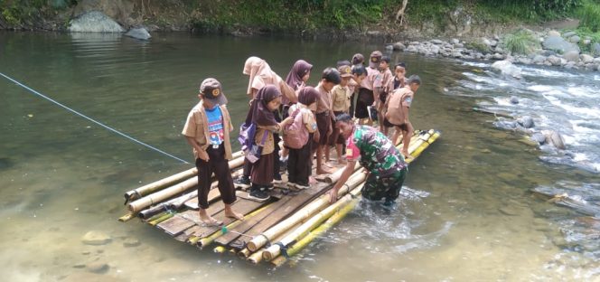 
					Jembatan Belum Terbangun, Babinsa Antar Anak-Anak Sekolah Menyebrang Sungai dengan Rakit Bambu di Tapua